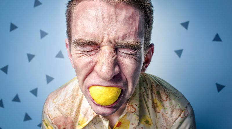 Mann beißt in Zitrone